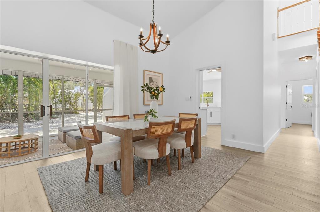 A dining area with a wooden table, cane-back chairs, and a chandelier near sliding doors — 4074 REDBIRD CIRCLE, SARASOTA, FL