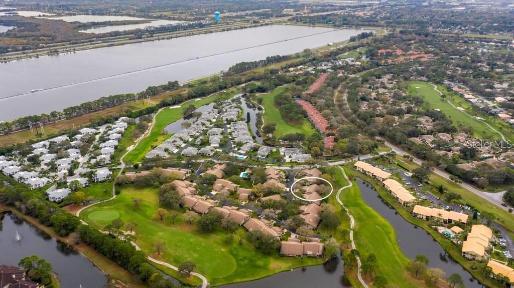An aerial view shows a residential community with townhomes, golf course fairways, and a lake — 4521 KINGSMERE UNIT 6, SARASOTA, FL