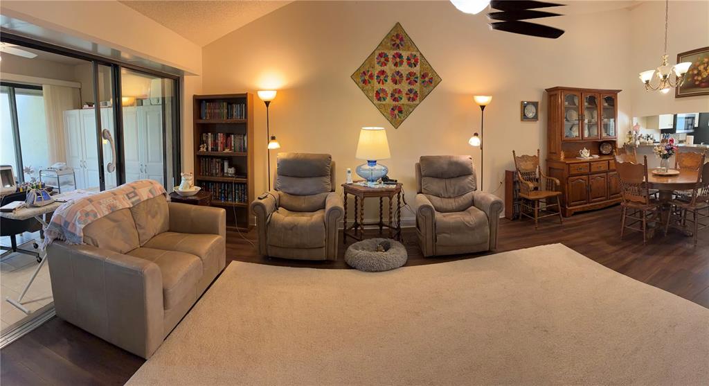 A living room features a beige sofa, two recliners, a bookshelf, and a dining area — 4521 KINGSMERE UNIT 6, SARASOTA, FL