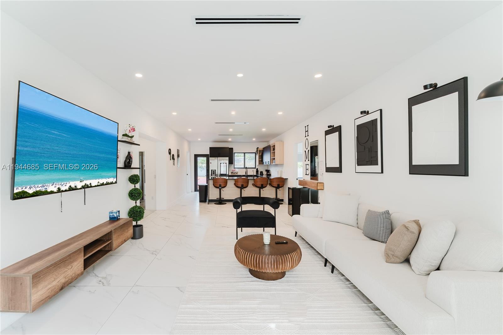 A modern open-concept living room and kitchen featuring white tile floors and neutral furniture — 187 NW 53rd St, Miami FL 33127, MIAMI, FL