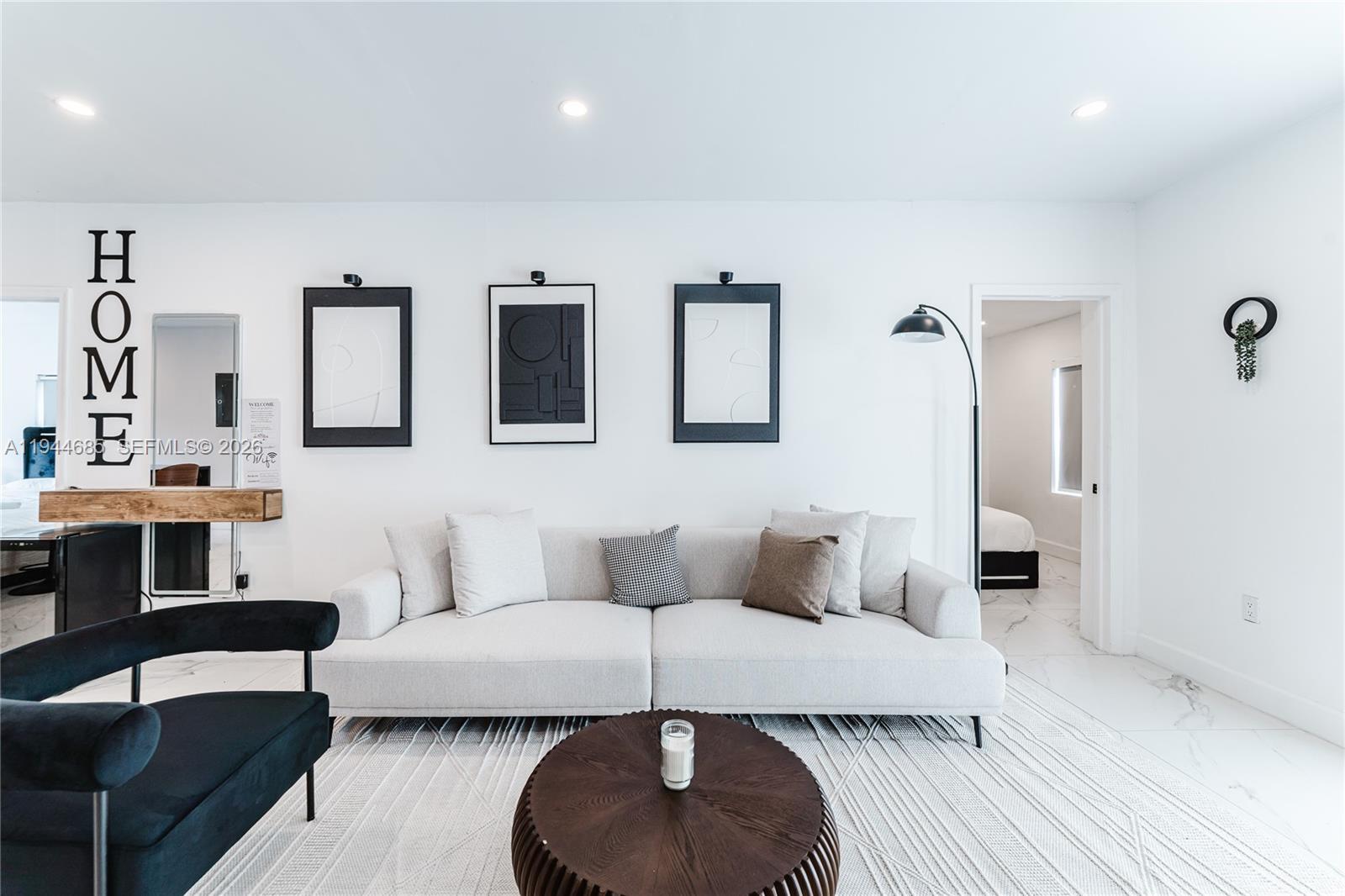 A modern living room features a light gray sofa, dark coffee table, and minimalist wall art — 187 NW 53rd St, Miami FL 33127, MIAMI, FL