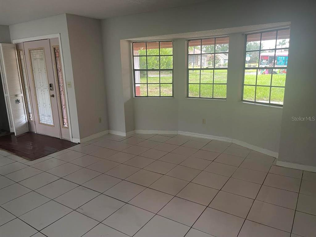 A room with light-colored tile flooring, gray walls, and three windows overlooking a yard — 9310 BAY VISTA ESTATES BOULEVARD, ORLANDO, FL