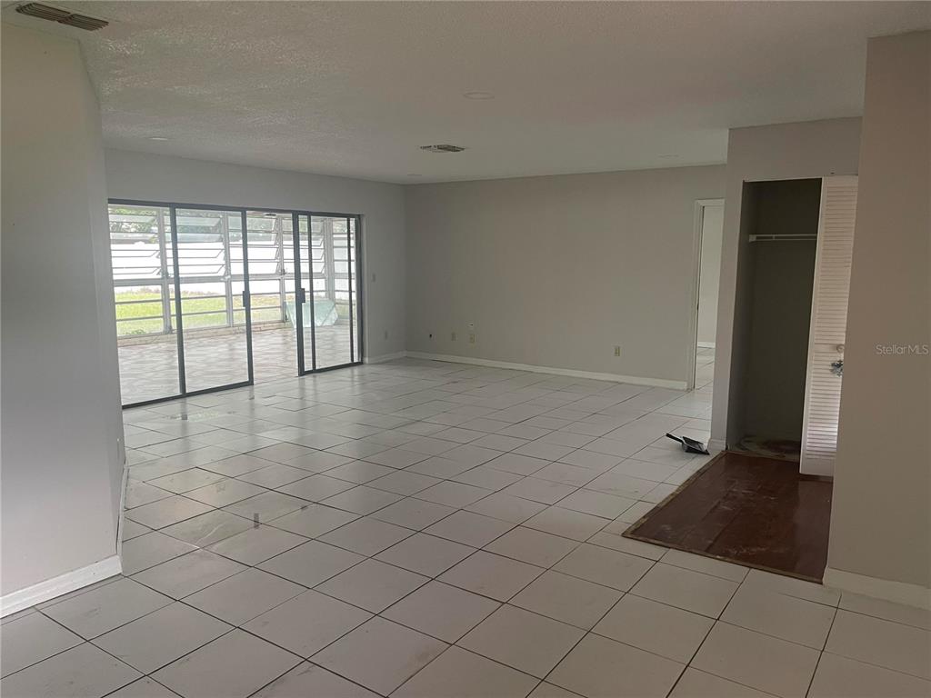 An empty room with white tile floors, light gray walls, and sliding glass patio doors — 9310 BAY VISTA ESTATES BOULEVARD, ORLANDO, FL