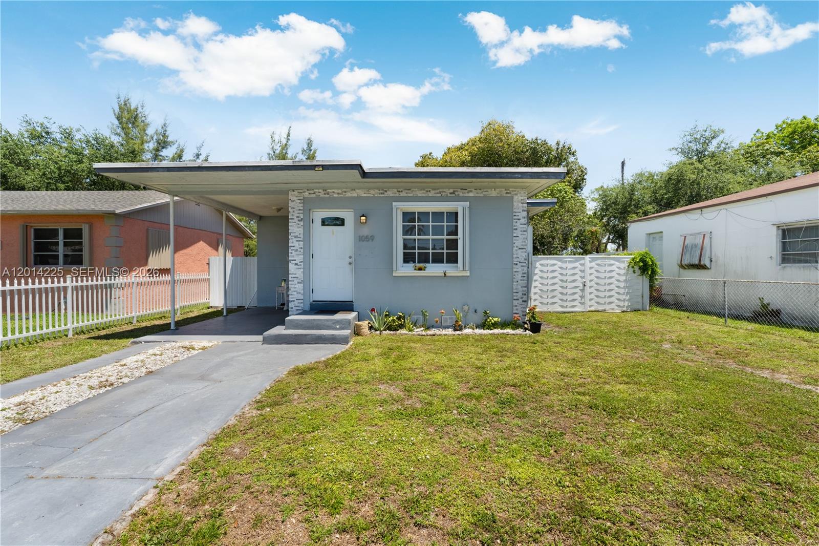 A gray single-story house features a flat roof, a carport, and a front lawn — 1059 NW 77th St, Miami FL 33150, MIAMI, FL
