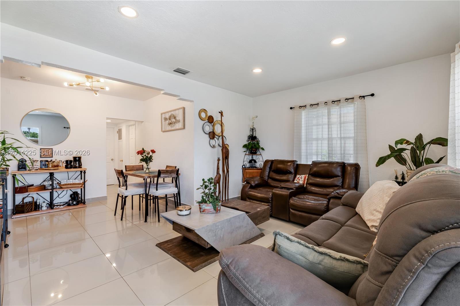 A living room and dining area feature white walls, tile flooring, and brown furniture — 1059 NW 77th St, Miami FL 33150, MIAMI, FL