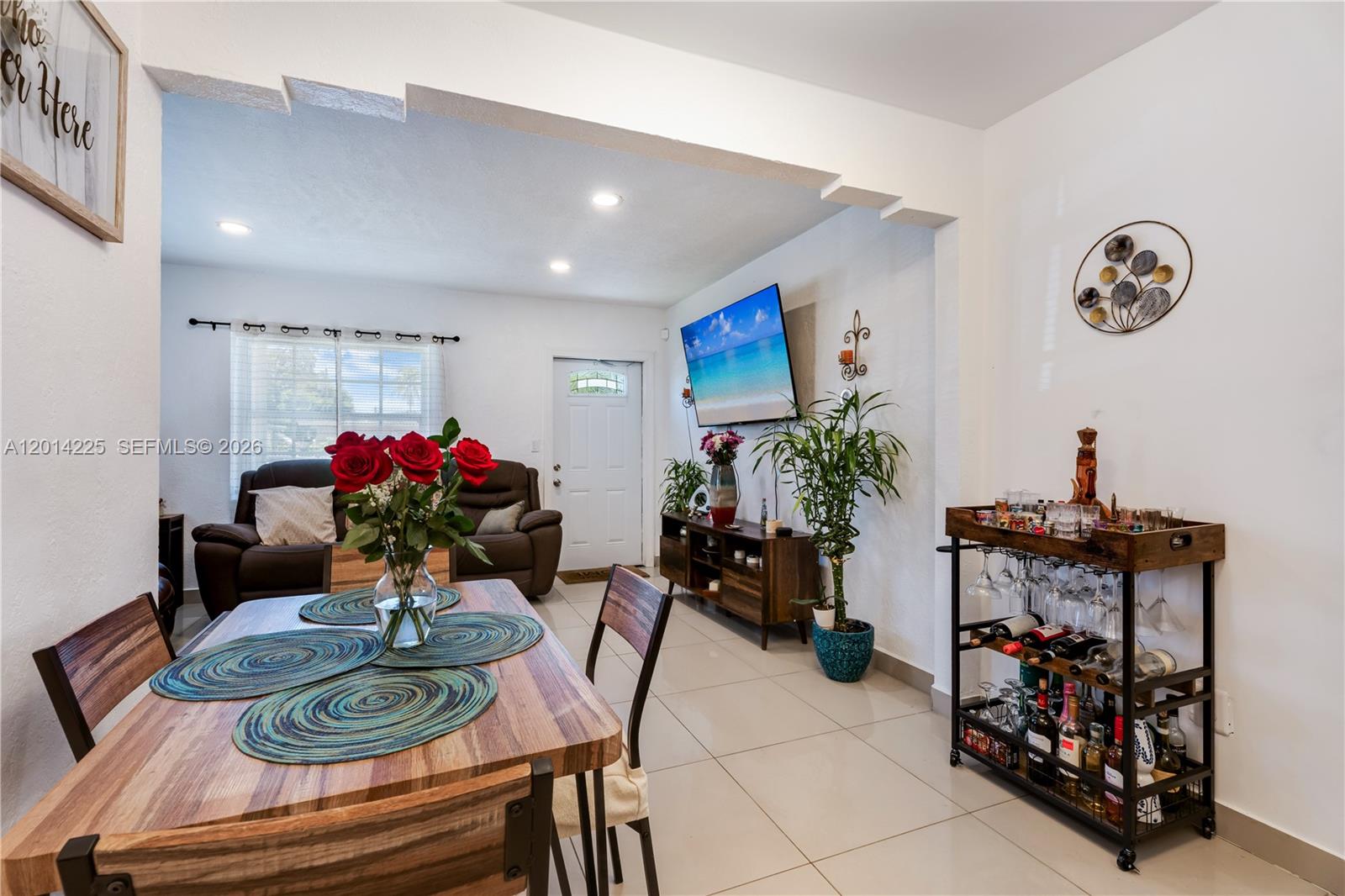 A dining area with a wooden table and bar cart opens into a living room — 1059 NW 77th St, Miami FL 33150, MIAMI, FL