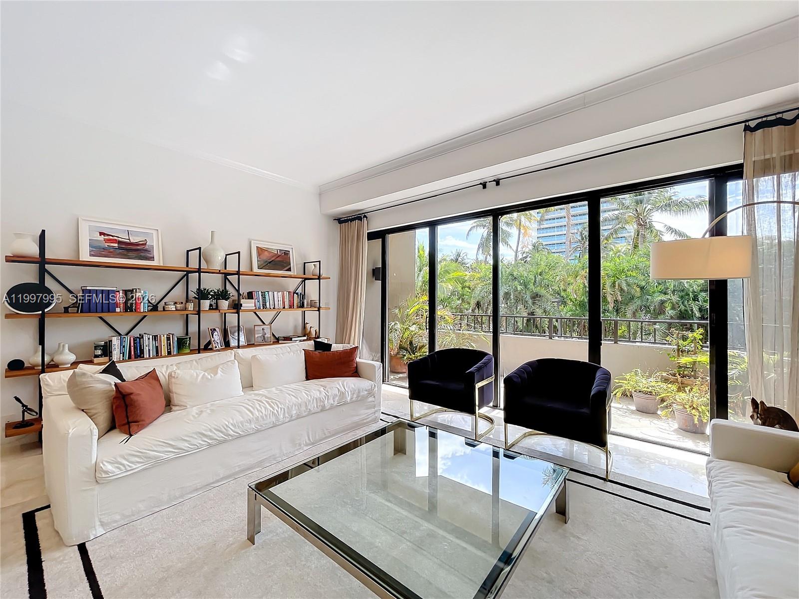 A living room features a white sofa, glass coffee table, dark armchairs, and floor-to-ceiling windows — 201 Crandon Blvd # 163, Key Biscayne FL 33149, KEY BISCAYNE, FL