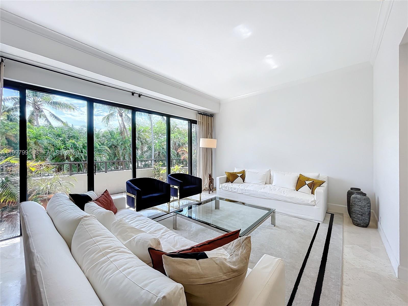 A living room features two white sofas, two navy armchairs, a glass coffee table, and floor-to-ceiling windows — 201 Crandon Blvd # 163, Key Biscayne FL 33149, KEY BISCAYNE, FL