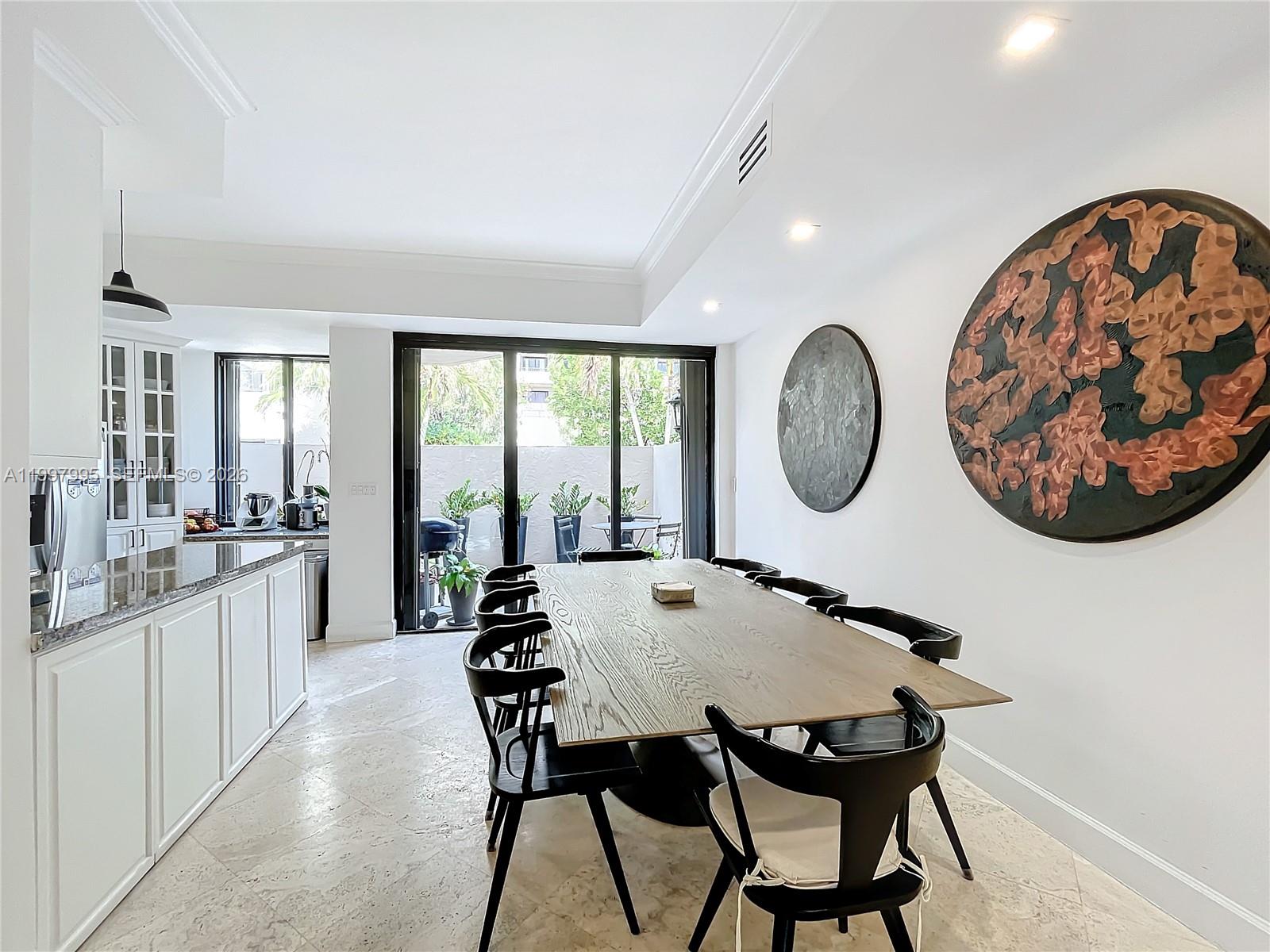 A dining room features a long wooden table, black chairs, and two large circular artworks — 201 Crandon Blvd # 163, Key Biscayne FL 33149, KEY BISCAYNE, FL