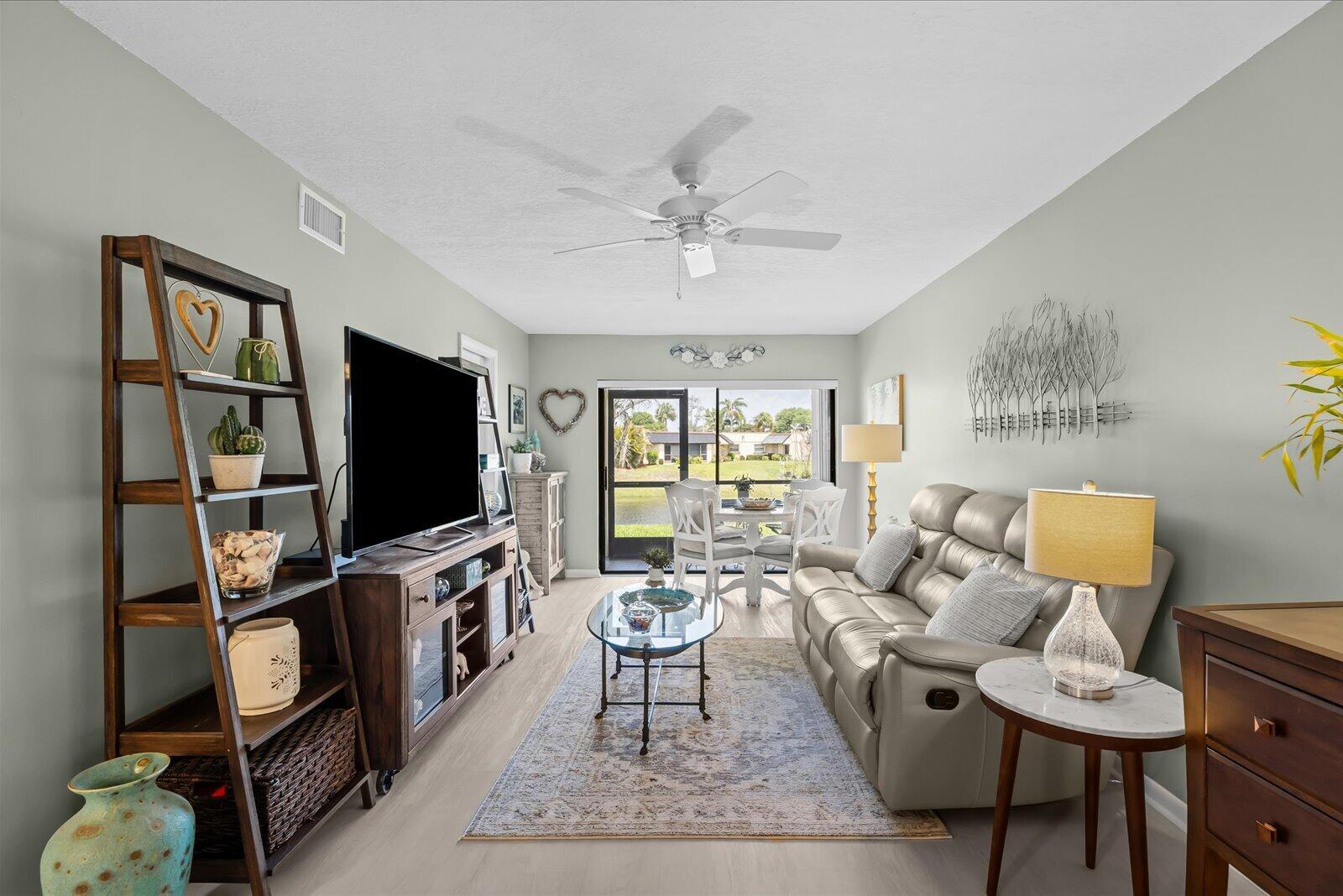 An entryway features a wooden sideboard, a gray tufted bench, and a white front door — 2069 NE Collins Circle # 50, Jensen Beach FL 34957, JENSEN BEACH, FL