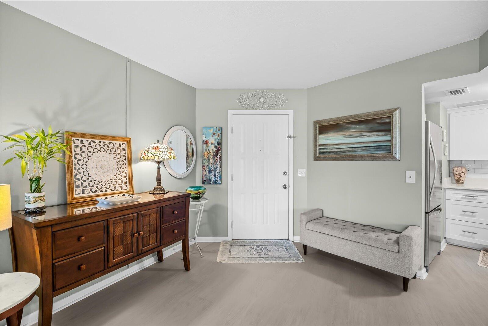A white kitchen with stainless steel appliances sits adjacent to an entryway with a bench — 2069 NE Collins Circle # 50, Jensen Beach FL 34957, JENSEN BEACH, FL