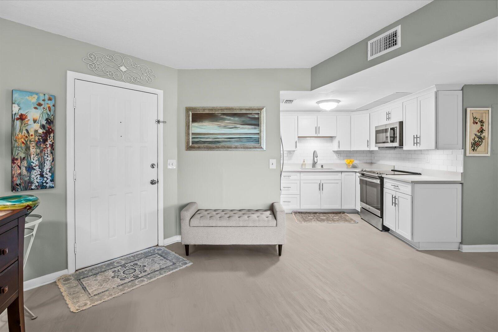 A galley kitchen features white cabinets, stainless steel appliances, and a white subway tile backsplash — 2069 NE Collins Circle # 50, Jensen Beach FL 34957, JENSEN BEACH, FL
