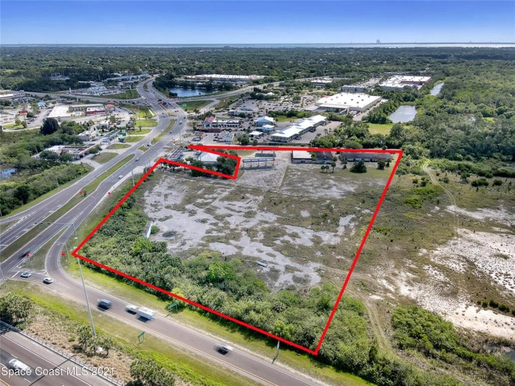 An aerial view of a large, vacant commercial lot outlined in red next to a highway — 8251 WINDOVER WAY, TITUSVILLE, FL