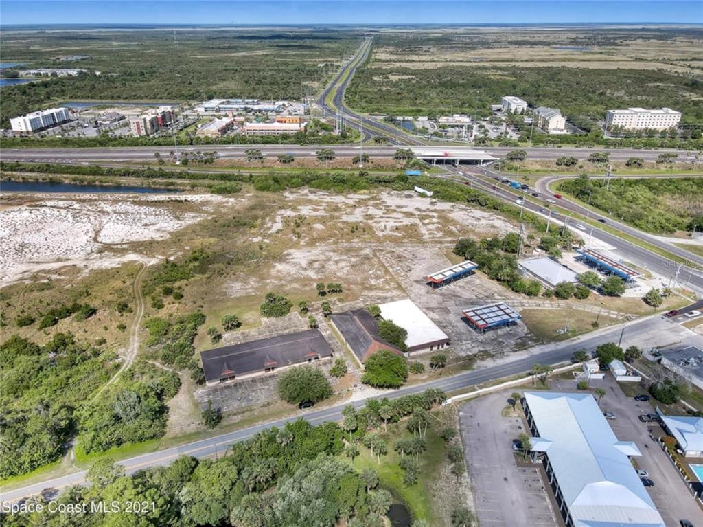 An aerial view shows a vacant lot with several buildings and a nearby highway interchange — 8251 WINDOVER WAY, TITUSVILLE, FL