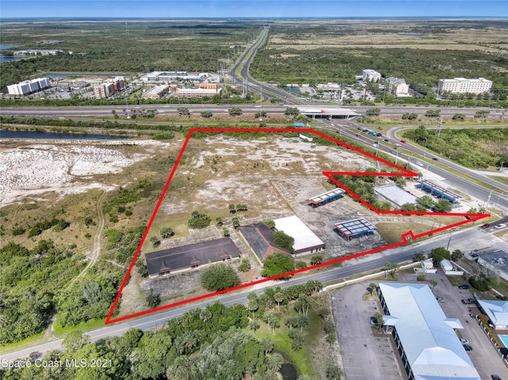 An aerial view shows a vacant lot with several existing buildings and paved areas — 8251 WINDOVER WAY, TITUSVILLE, FL