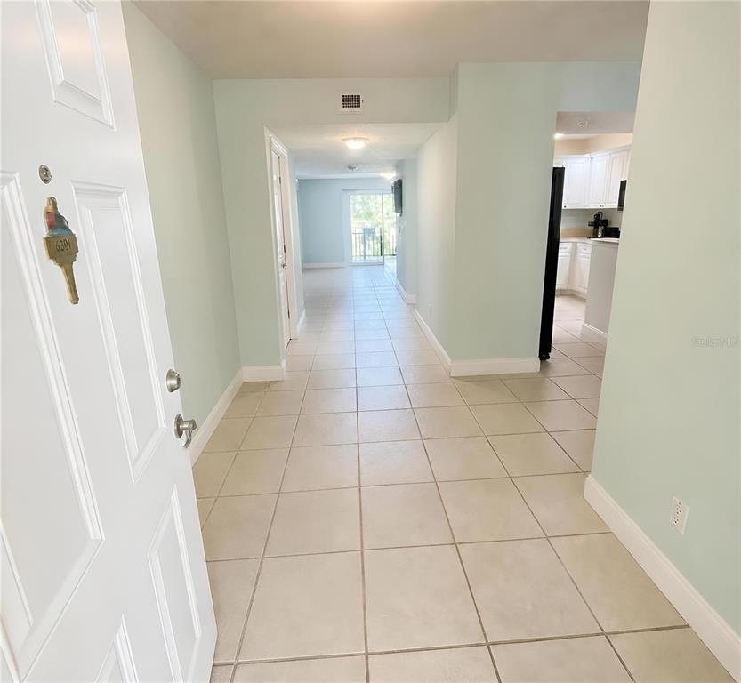 An entryway with light-colored tile flooring leads toward a kitchen and a living area — 4670 LINKS VILLAGE DRIVE UNIT B301, PONCE INLET, FL