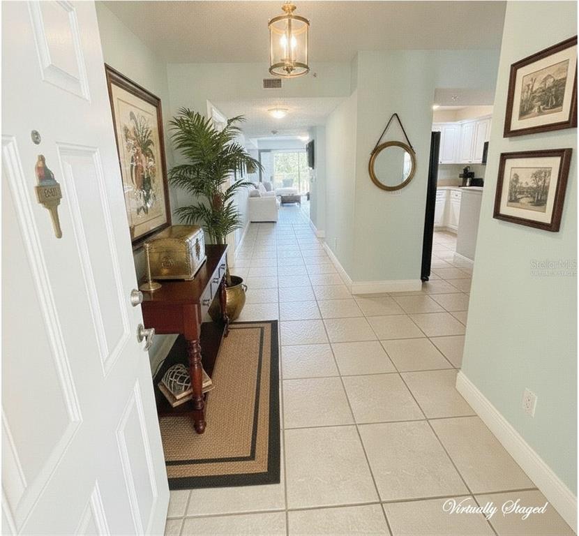 A tiled entryway leads into a hallway with a console table and a kitchen view — 4670 LINKS VILLAGE DRIVE UNIT B301, PONCE INLET, FL