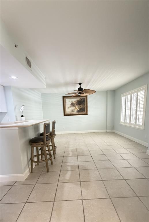 A room with light-colored tile flooring, a breakfast bar with stools, and a ceiling fan — 4670 LINKS VILLAGE DRIVE UNIT B301, PONCE INLET, FL