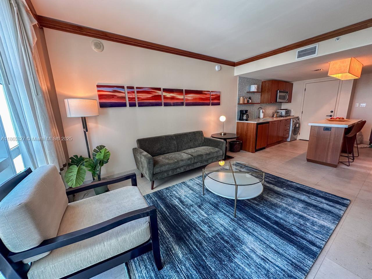 A living room with a sofa, armchair, coffee table, and an open kitchen area — 6801 Collins Ave # 815, Miami Beach FL 33141, MIAMI BEACH, FL