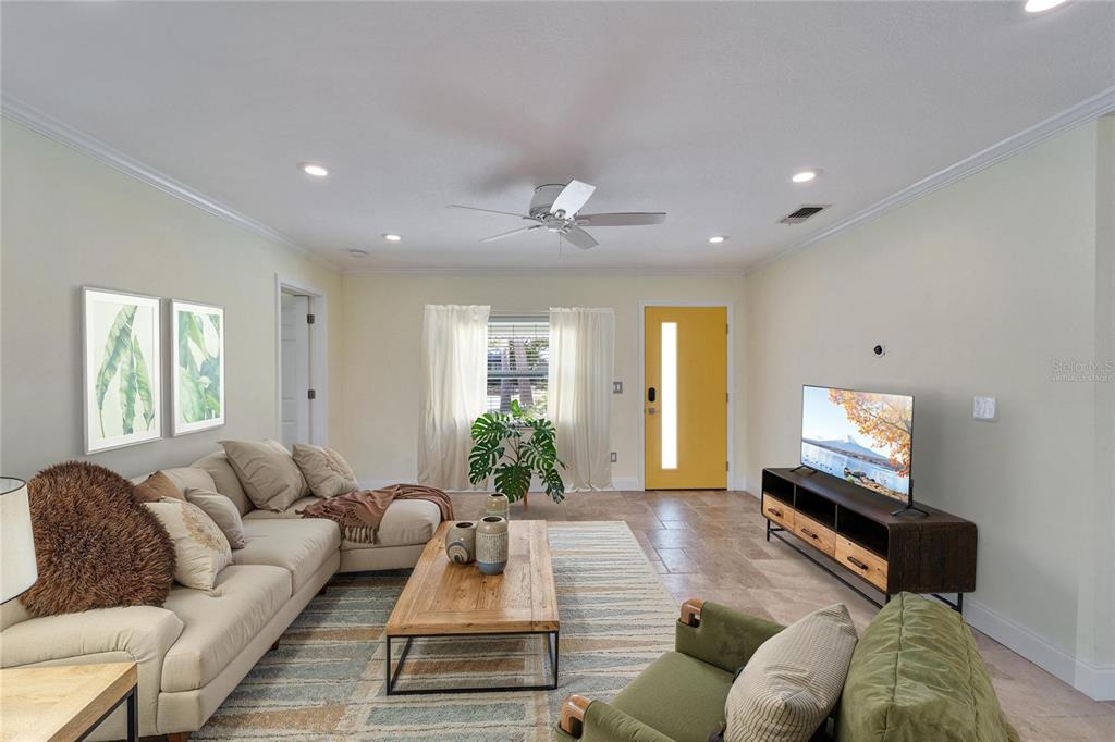 A living room features a sectional sofa, a wooden coffee table, and a yellow door — 8702 DRIFTWOOD DRIVE, TAMPA, FL