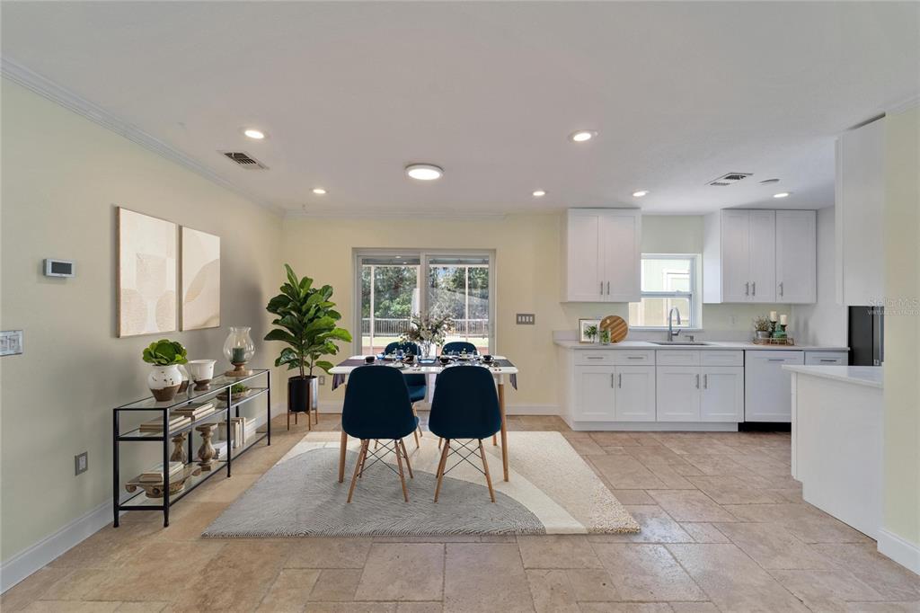 A dining area with a table, four blue chairs, and a kitchen with white cabinets — 8702 DRIFTWOOD DRIVE, TAMPA, FL
