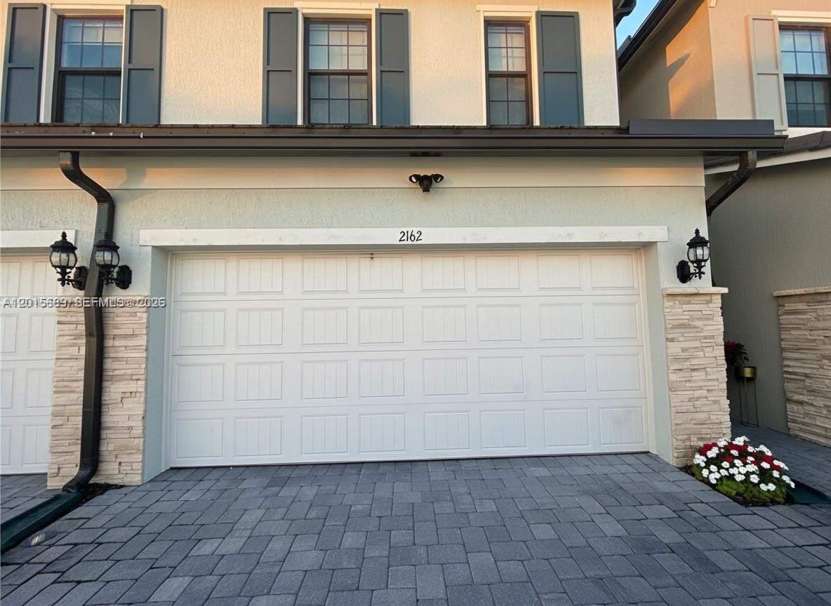 The exterior of a two-story home features a white garage door and stone accents — 2162 Appleton Cir N, Oakland Park FL 33309, OAKLAND PARK, FL