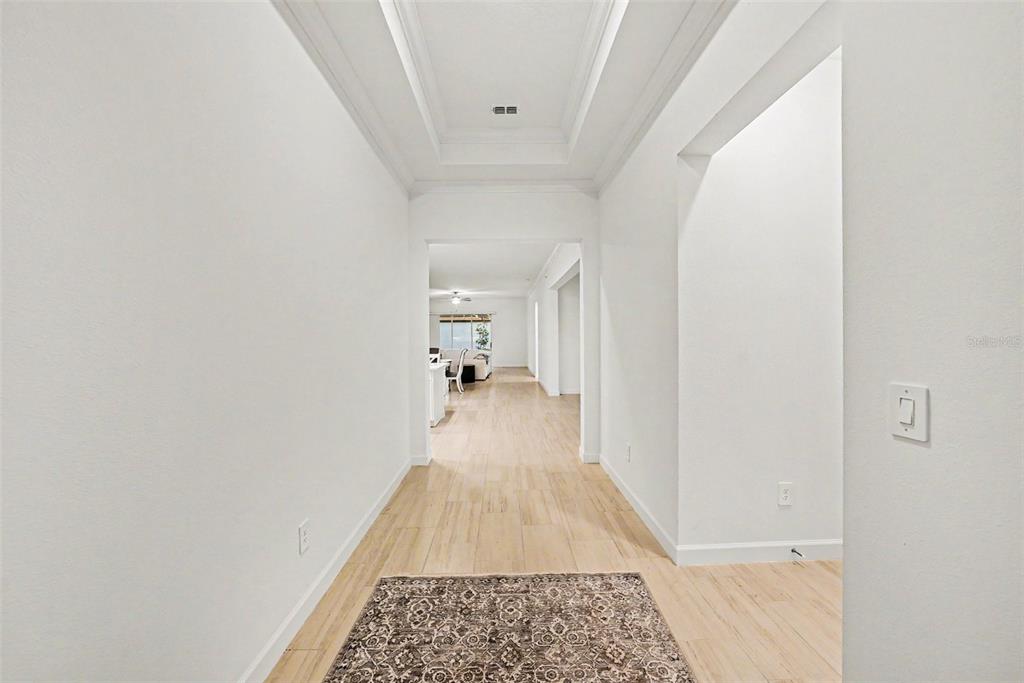 A bright hallway with light wood-look flooring leads to an open living area — 17415 HOLLY WELL AVENUE, WIMAUMA, FL