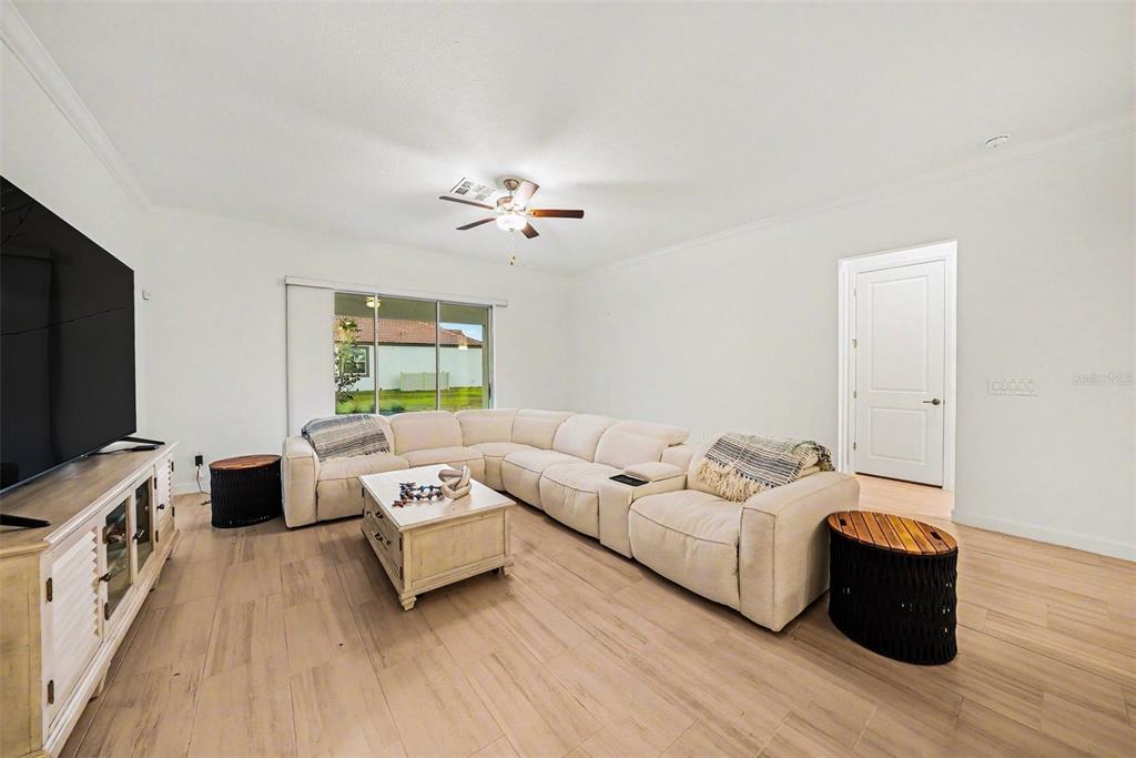 A living room features a large white sectional, a coffee table, and light wood-look flooring — 17415 HOLLY WELL AVENUE, WIMAUMA, FL
