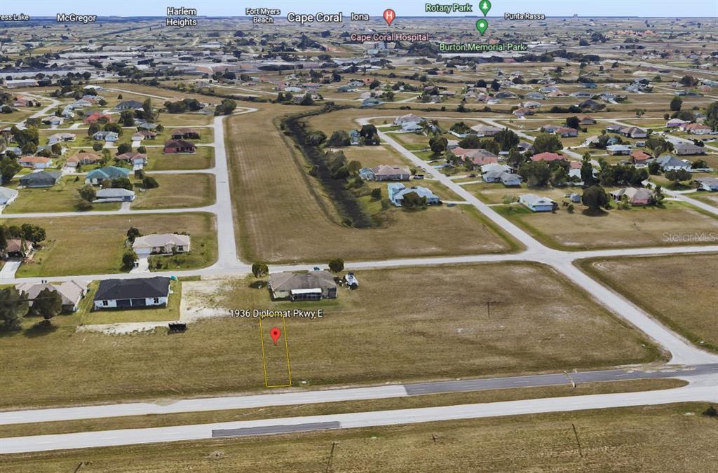An aerial view shows a vacant residential lot next to a house in a neighborhood — 1936 DIPLOMAT PARKWAY E, CAPE CORAL, FL