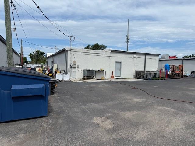 A large blue dumpster sits in the paved parking lot of a white commercial building — 9511 N NEBRASKA AVENUE, TAMPA, FL