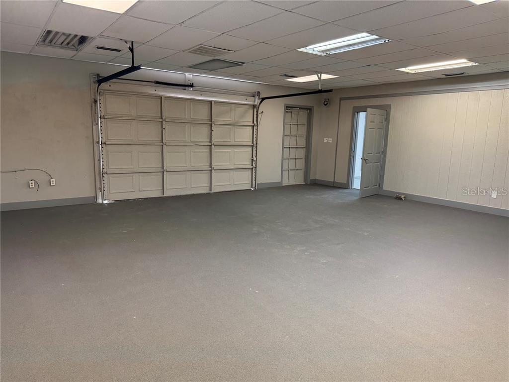 A garage with a gray floor, drop ceiling, and two doors leading to other rooms — 9511 N NEBRASKA AVENUE, TAMPA, FL
