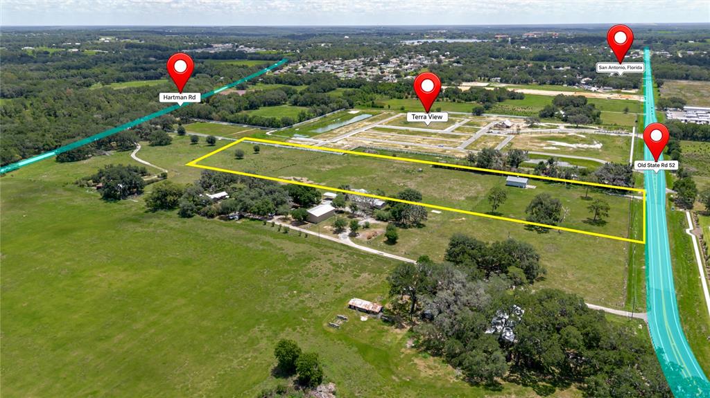 This aerial view shows a large, rectangular plot of land with buildings and trees — 31641 COUNTY ROAD 52, SAN ANTONIO, FL