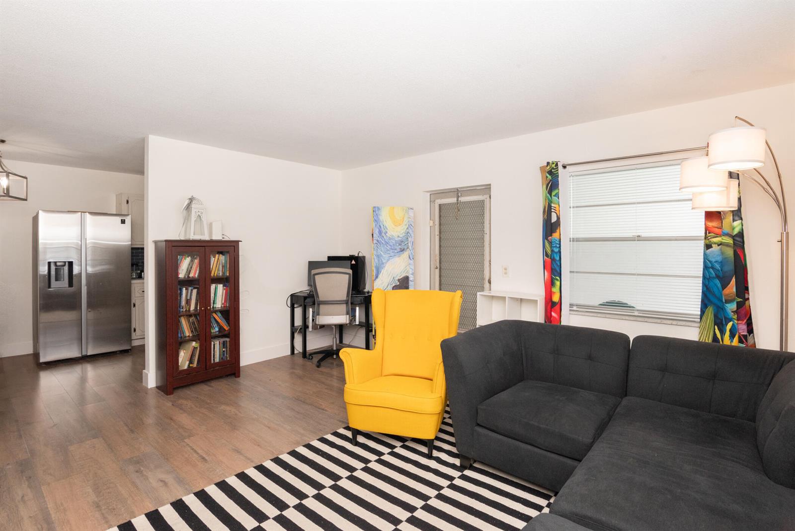 A living room features a dark sectional sofa, a yellow armchair, and a bookshelf — 401 N J Street # 9, FL 33460, FL