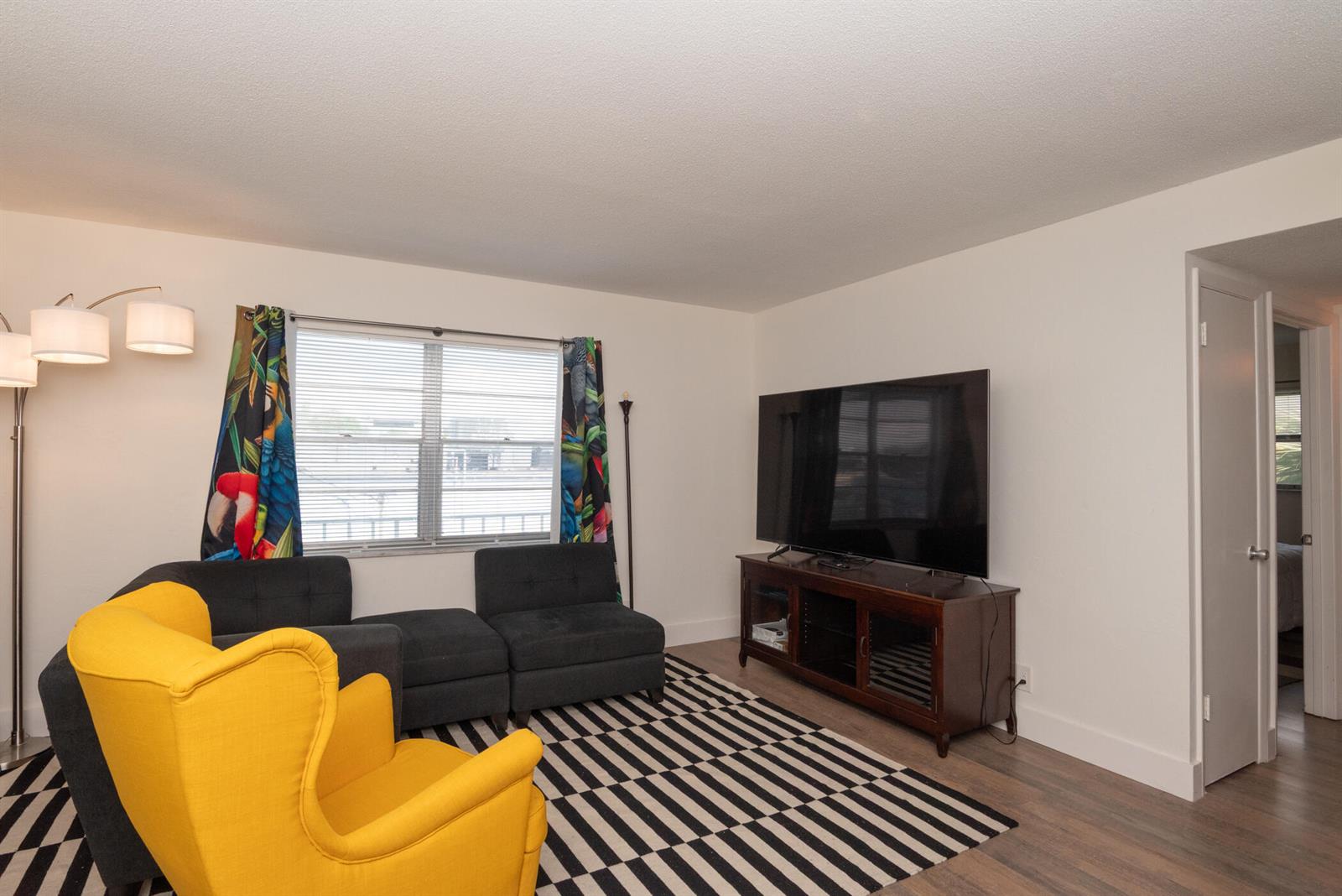 A living room features a yellow armchair, a dark sectional, and a television on a stand — 401 N J Street # 9, FL 33460, FL