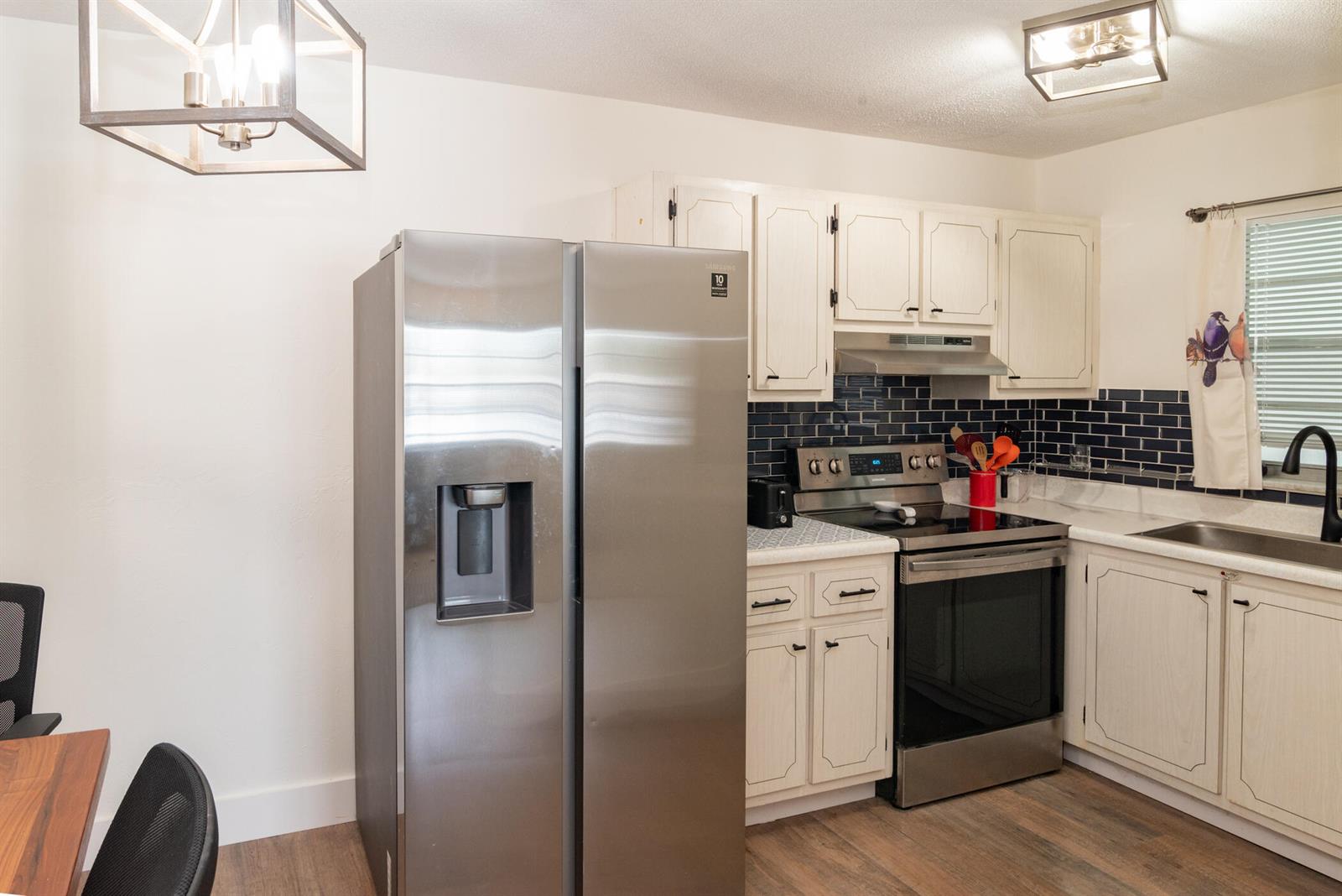 A kitchen features stainless steel appliances, white cabinets, and a dark blue subway tile backsplash — 401 N J Street # 9, FL 33460, FL