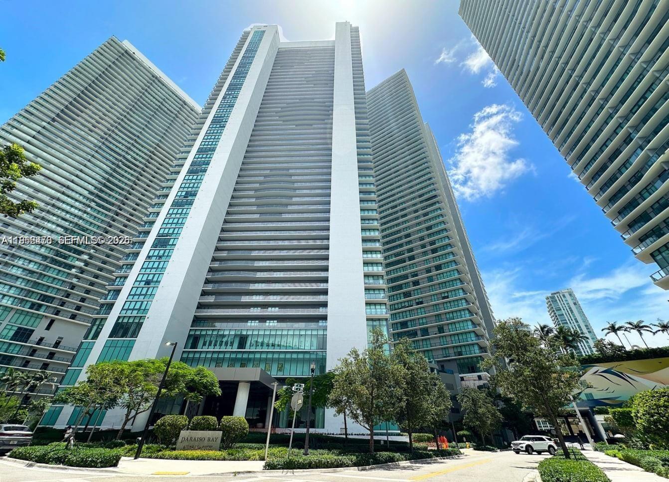 A low-angle exterior view of the tall Paraiso Bay residential tower under a blue sky — 650 NE 32nd St, Miami FL 33137, MIAMI, FL