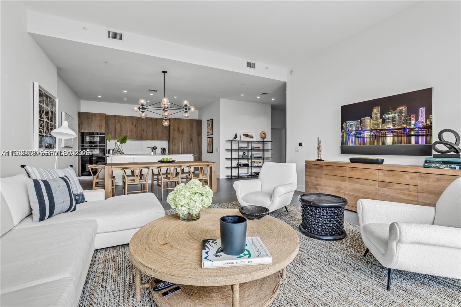 A modern open-concept living room features a white sofa, two armchairs, and a wooden dining area — 650 NE 32nd St, Miami FL 33137, MIAMI, FL
