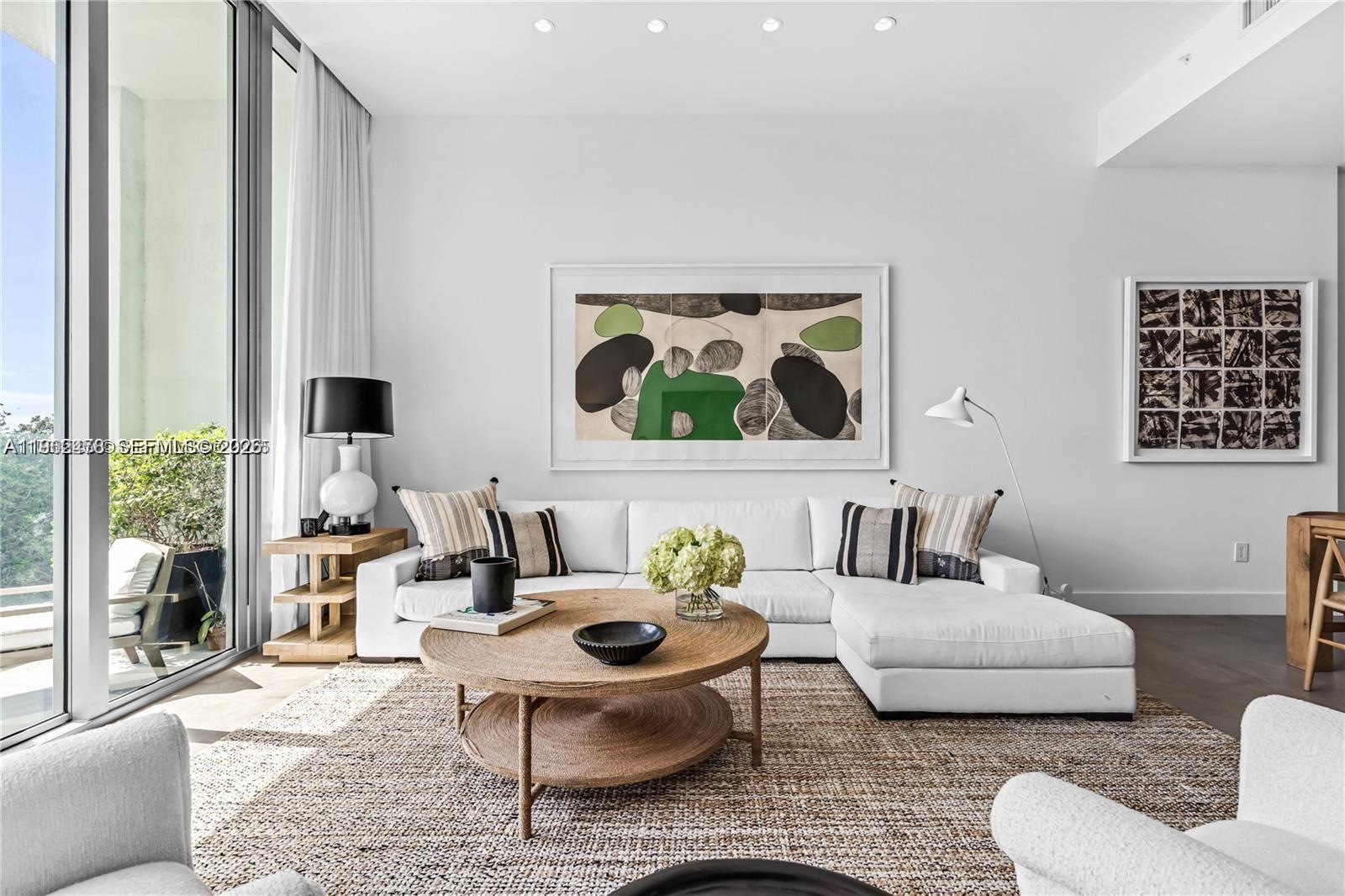 A bright living room features a white sectional sofa, a round wooden coffee table, and abstract art — 650 NE 32nd St, Miami FL 33137, MIAMI, FL