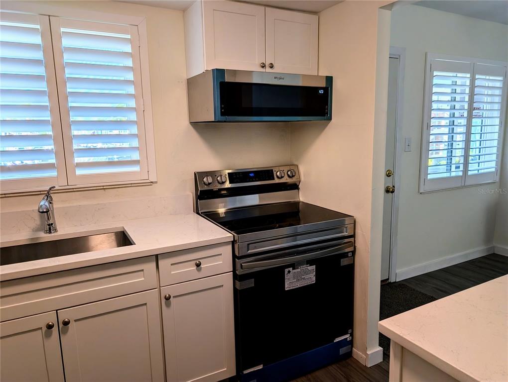 A kitchen features white cabinets, a stainless steel range, a microwave, and a white countertop — 5862 WELCOME ROAD UNIT #J-25, BRADENTON, FL