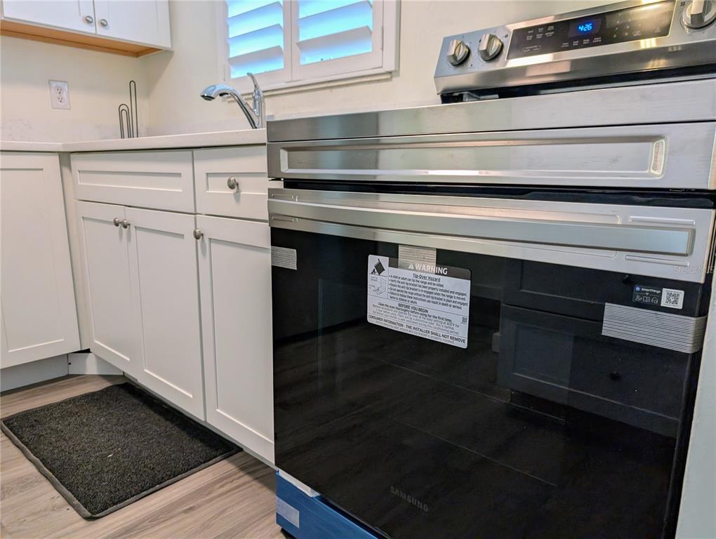A stainless steel Samsung oven sits next to white kitchen cabinets and a sink — 5862 WELCOME ROAD UNIT #J-25, BRADENTON, FL