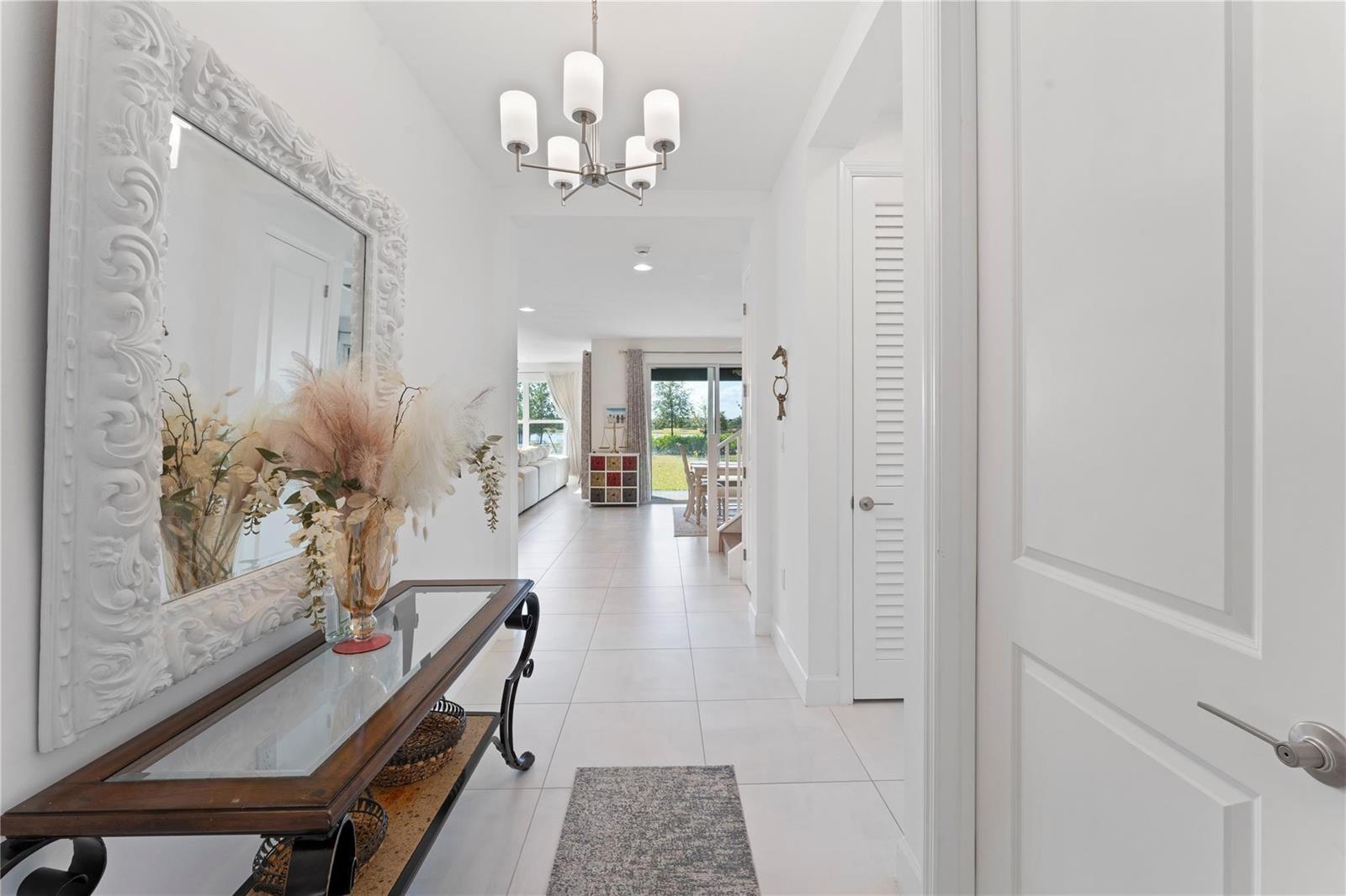 A bright hallway features white tile floors, a decorative mirror, and a glass-topped console table — 19552 Broad Shore Walk, Loxahatchee FL 33470, LOXAHATCHEE, FL