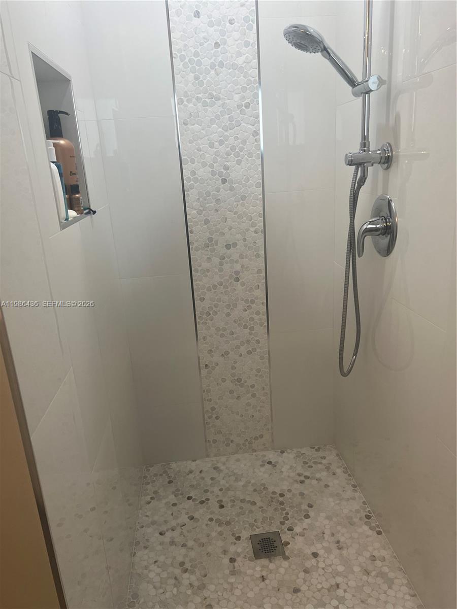 A walk-in shower features white wall tiles, a pebble-tiled accent strip, and a pebble floor — 8221 NW 14th St, Plantation FL 33322, PLANTATION, FL