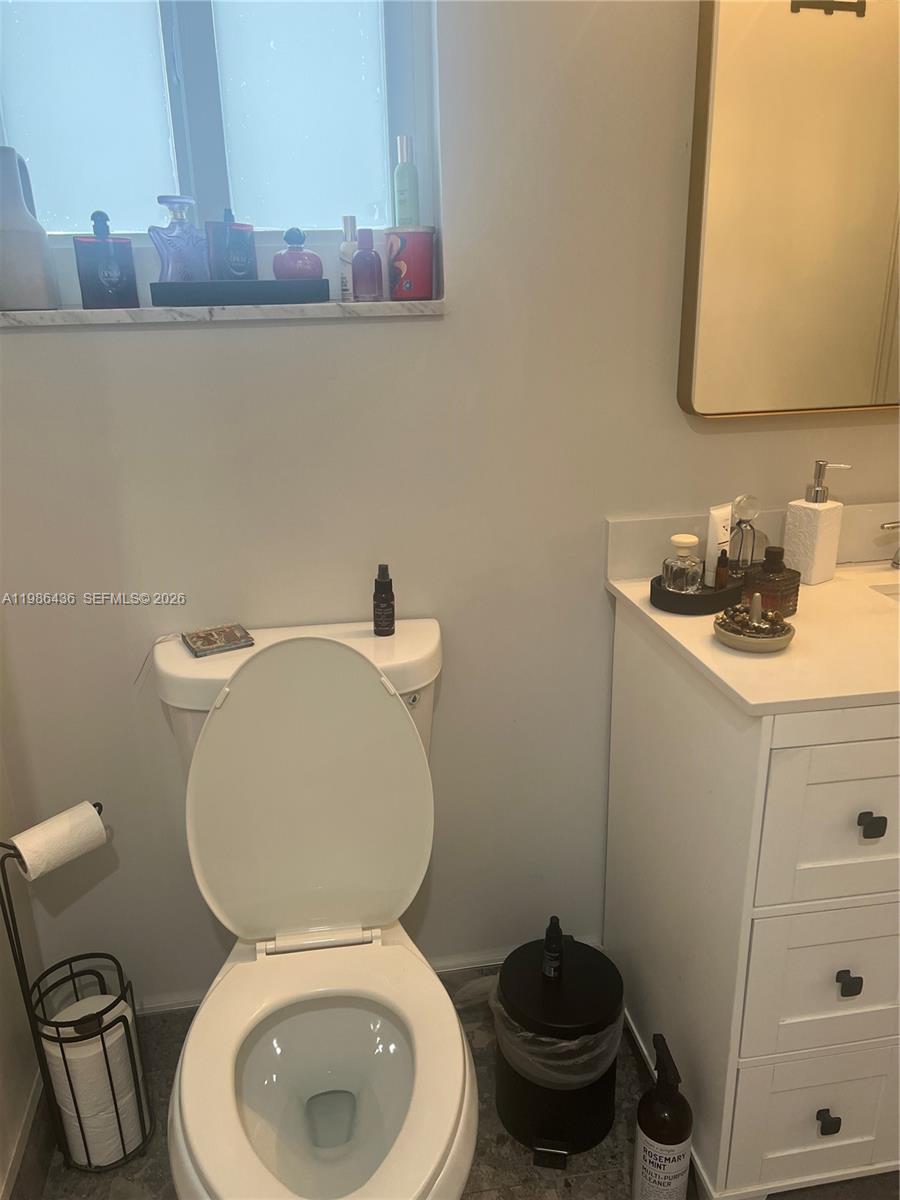 A bathroom features a white toilet, a vanity with a mirror, and a window ledge — 8221 NW 14th St, Plantation FL 33322, PLANTATION, FL