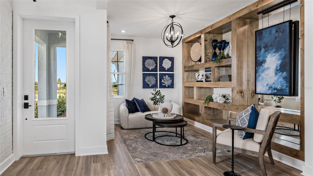 A bright entryway features a white door, wood-look flooring, a seating area, and built-in shelving — 1452 SANTORINI WAY, TAVARES, FL