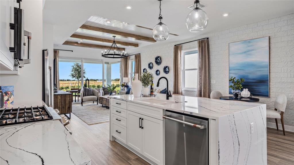 A kitchen with a white marble island and stainless steel appliances overlooks a living area — 1452 SANTORINI WAY, TAVARES, FL