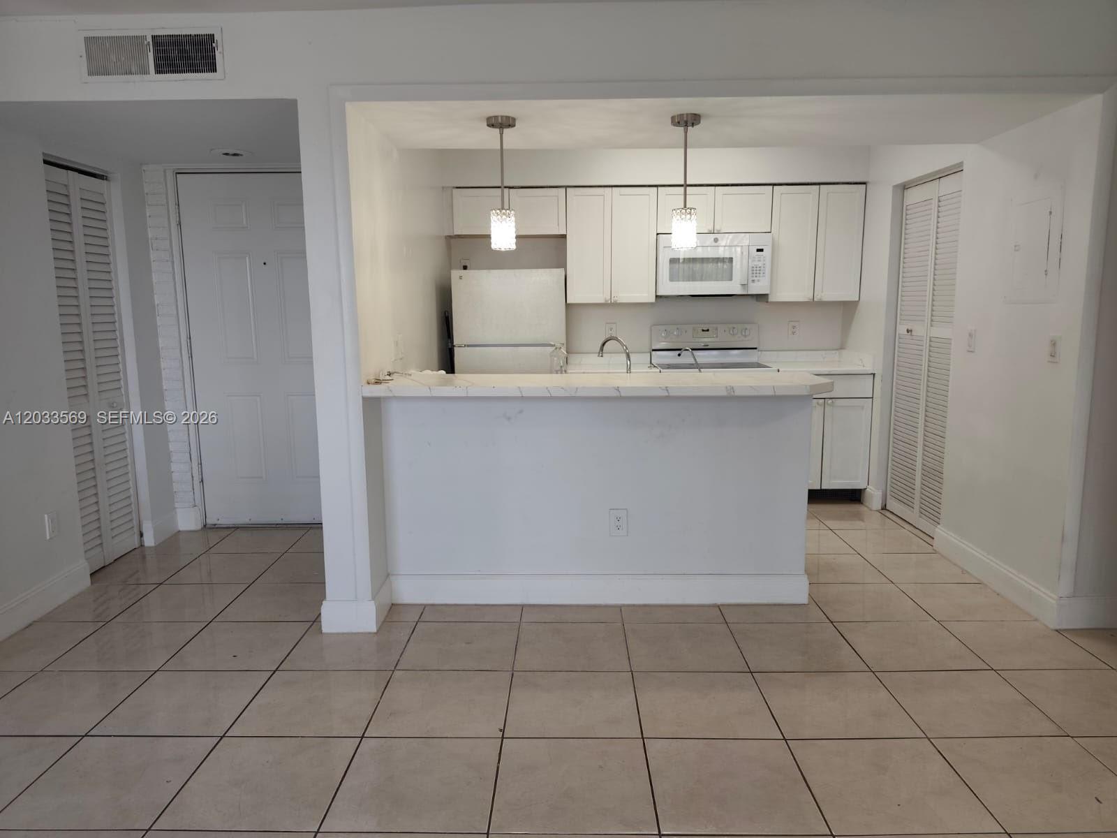 A kitchen with white cabinets, a marble-look countertop, and tile flooring — 1269 SW 46th Ave # 2408, Pompano Beach FL 33069, POMPANO BEACH, FL