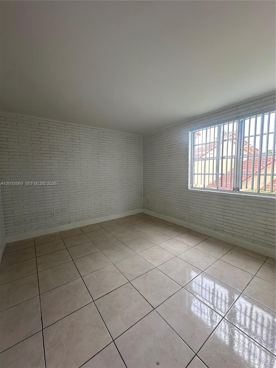 An empty room features white painted brick walls, light-colored tile flooring, and a window with bars — 1269 SW 46th Ave # 2408, Pompano Beach FL 33069, POMPANO BEACH, FL
