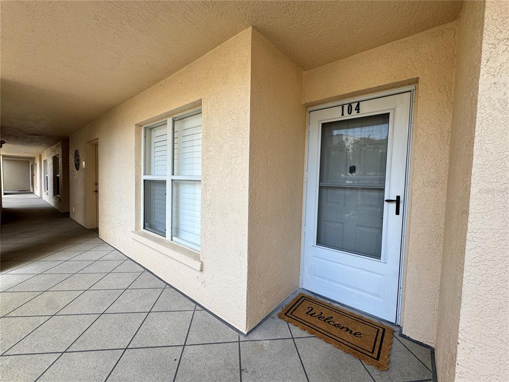 An exterior view of a residential unit entrance with a white door numbered 104 — 4110 IRONWOOD CIRCLE UNIT 104, BRADENTON, FL