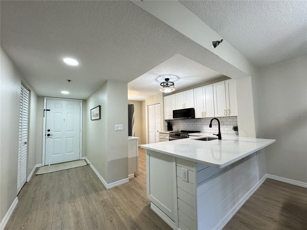 A kitchen with white cabinets and a quartz-topped island opens into an entryway — 4110 IRONWOOD CIRCLE UNIT 104, BRADENTON, FL