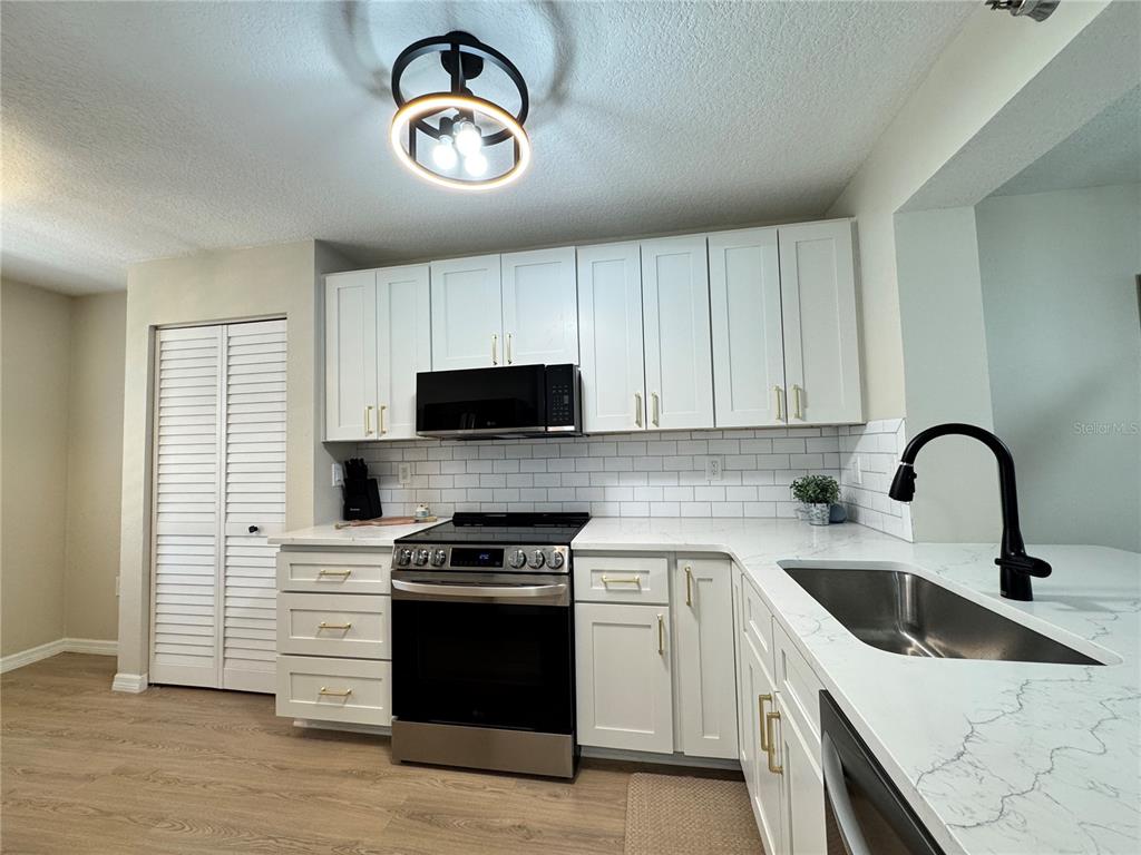 A kitchen featuring white cabinets, stainless steel appliances, a subway tile backsplash, and quartz countertops — 4110 IRONWOOD CIRCLE UNIT 104, BRADENTON, FL